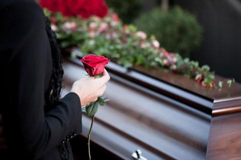 Hand holding a rose at the funeral