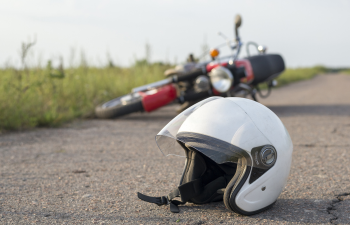 White motorcycle helmet on the road with a fallen motorcycle in the background.