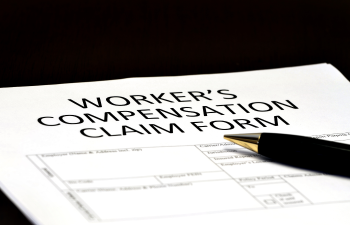 Worker's Compensation Claim Form partially filled out, with a black and gold pen resting on it.