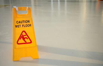 Yellow "Caution Wet Floor" sign on an empty, shiny floor under soft lighting.